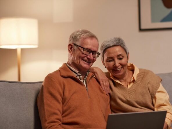 Senior couple enjoying time together on laptop indoors, smiling and relaxed.