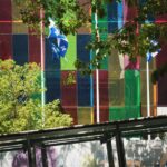 Vibrant glass building with Canadian and Quebec flags in downtown Montreal.